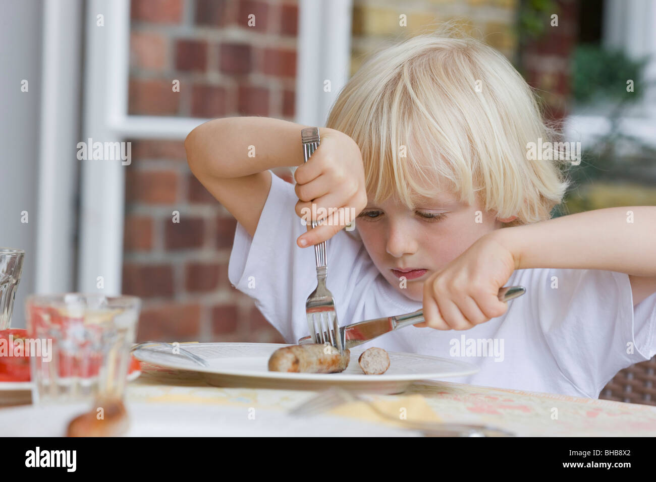 Ragazzo di mangiare con coltello e forchetta Foto Stock