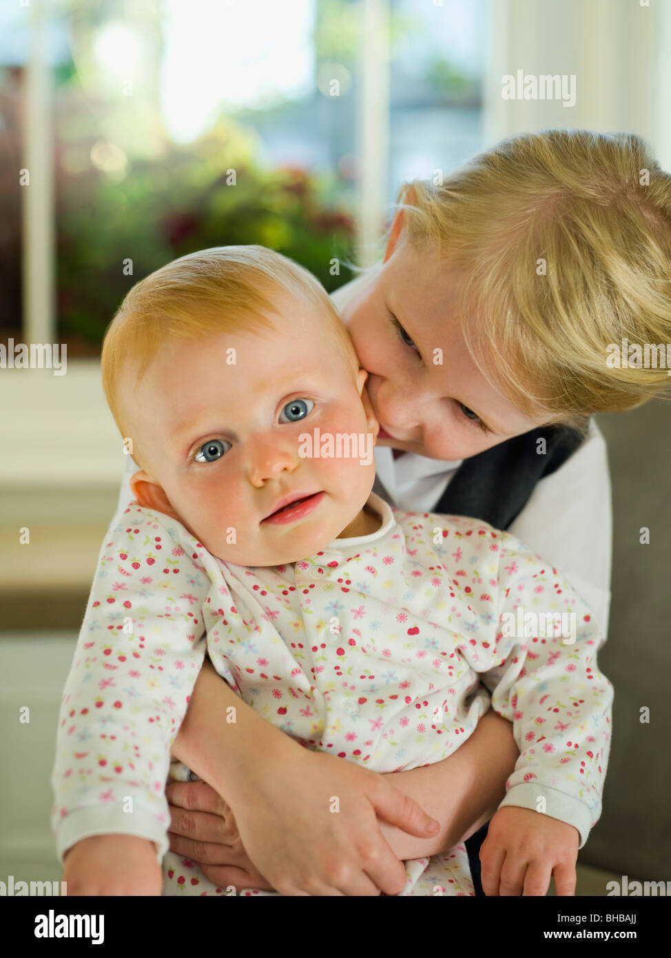 Una bambina che abbraccia il suo bambino sorella Foto Stock