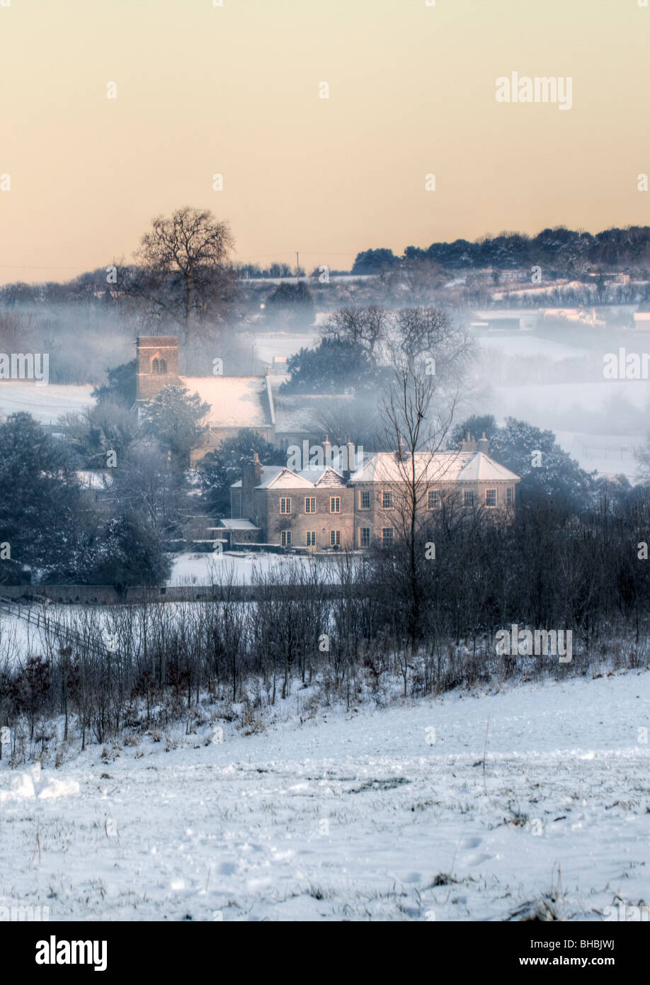 Il pittoresco neve invernale scena della St Anne's Chiesa e case di villaggio Siston vicino a Bristol, South Gloucestershire presi all'alba Foto Stock