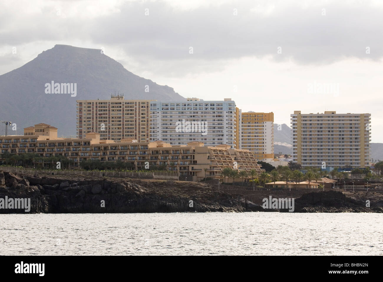 Le montagne vulcaniche torre sopra gli alberghi ed edifici di appartamenti a Playa de las Americas sulla costa di Tenerife, Spagna. Foto Stock