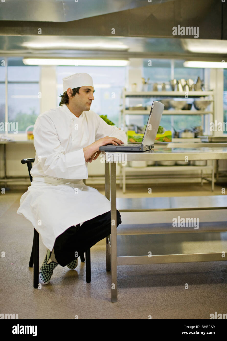 Un Cuoco a lavorare al suo computer portatile Foto Stock