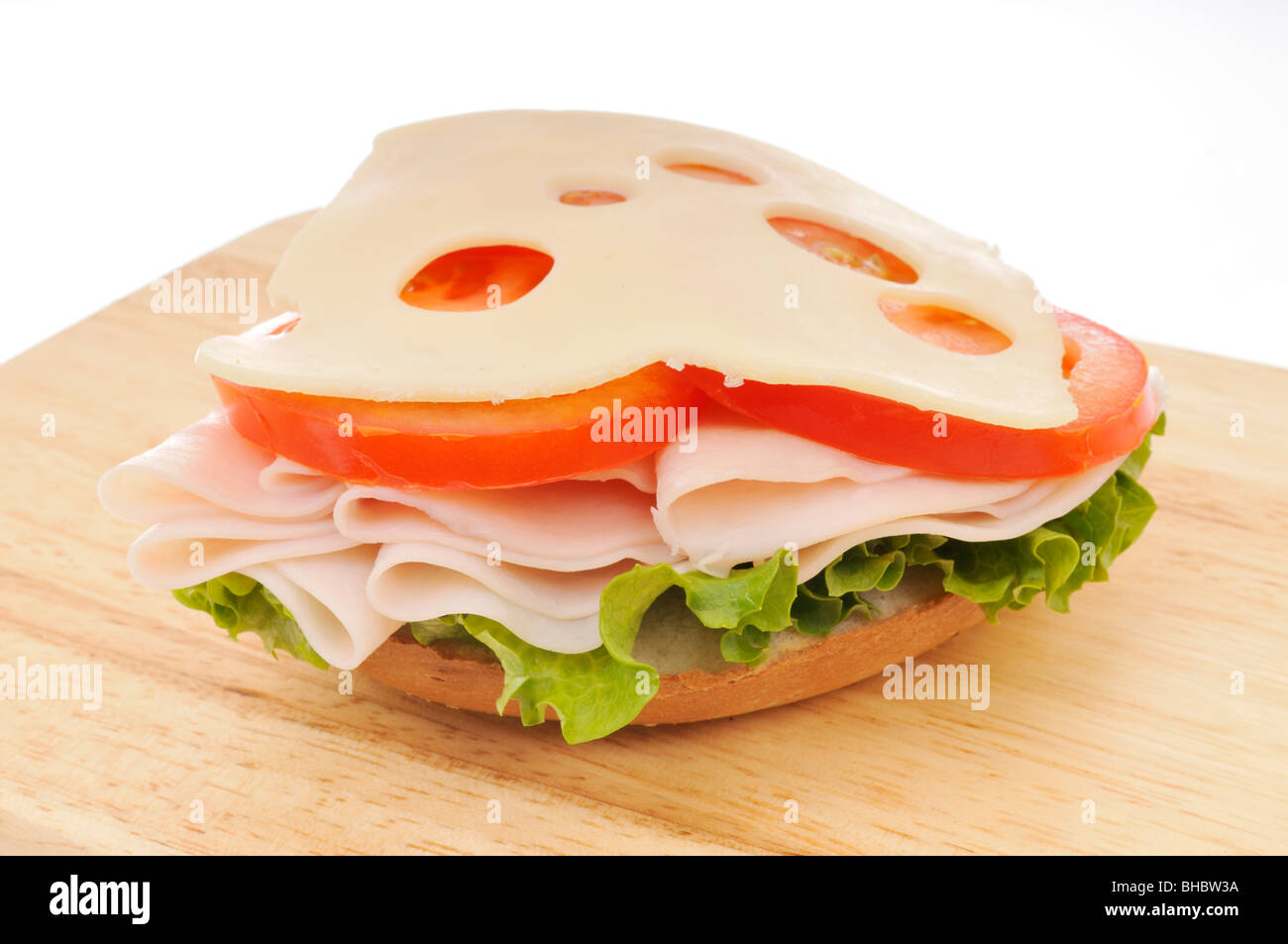 Aprire la Turchia il formaggio svizzero sandwich con lattuga e pomodoro su un bagel su un tagliere. Sfondo bianco. Foto Stock