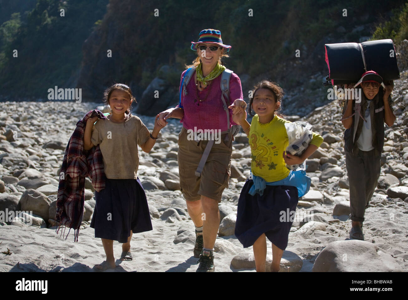 Christine Kolisch passeggiate mano nella mano con bambini nepalesi in BUDHI GANDAKI il letto del fiume - circa il MANASLU TREK, NEPAL Foto Stock