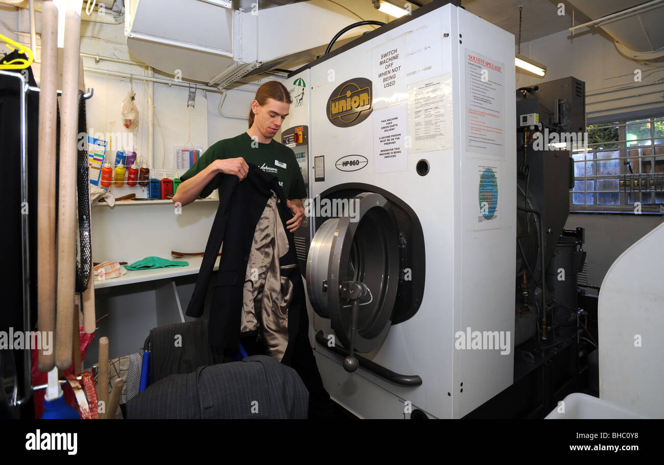 Un uomo lo scarico della grande macchina di lavaggio in Johnsons le lavanderie a secco di Burgess Hill Foto Stock