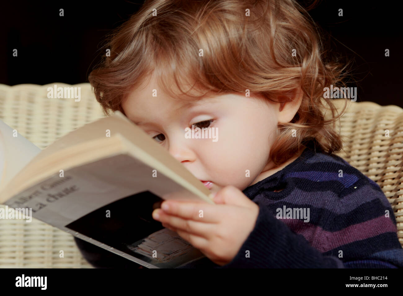 A venti mesi Baby girl nel senso che essa legge per reale di un libro del filosofo francese Albert Camus Foto Stock