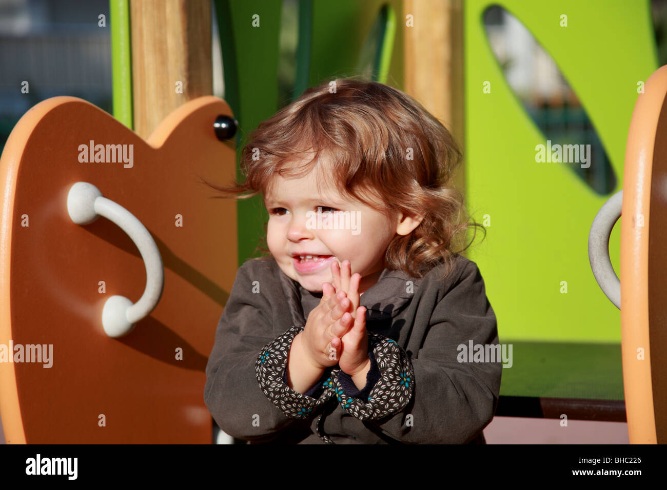 A venti mesi bambina gioca su una diapositiva in un giardino pubblico Foto Stock