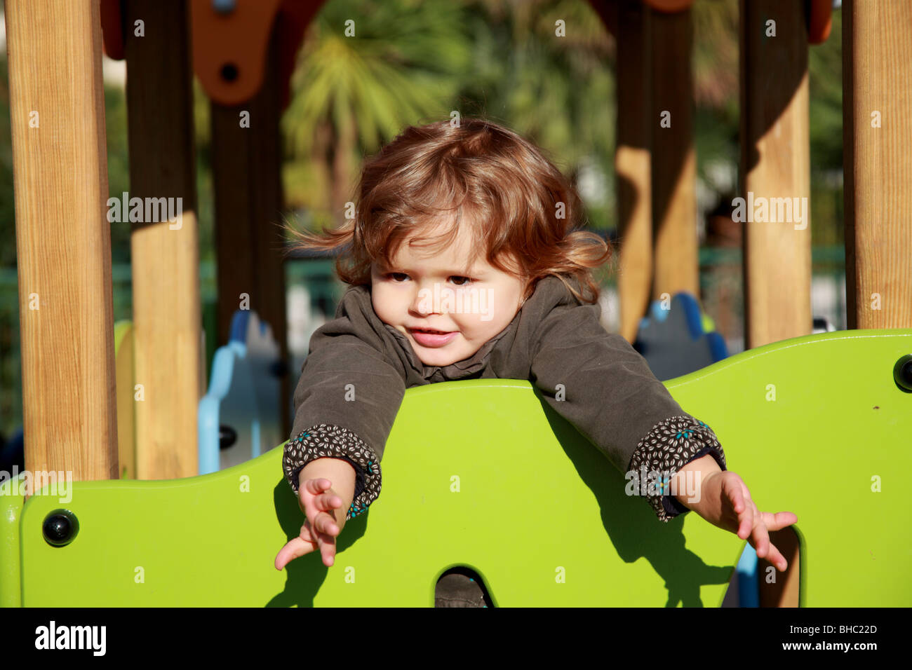 A venti mesi bambina gioca su una diapositiva in un giardino pubblico Foto Stock
