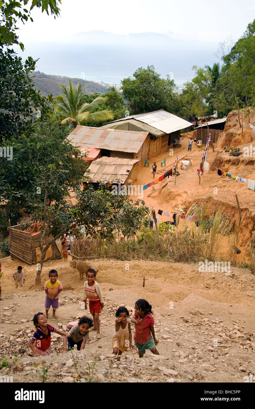 I bambini sulla collina sopra remoto villaggio montano di capanne dove gli agricoltori poveri suini da allevamento a Timor Est Foto Stock