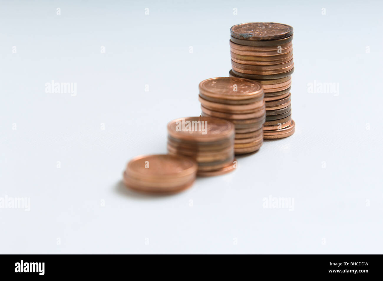 4 pile di monete shot su uno sfondo bianco. Ogni pila aumenta in dimensione. Foto Stock