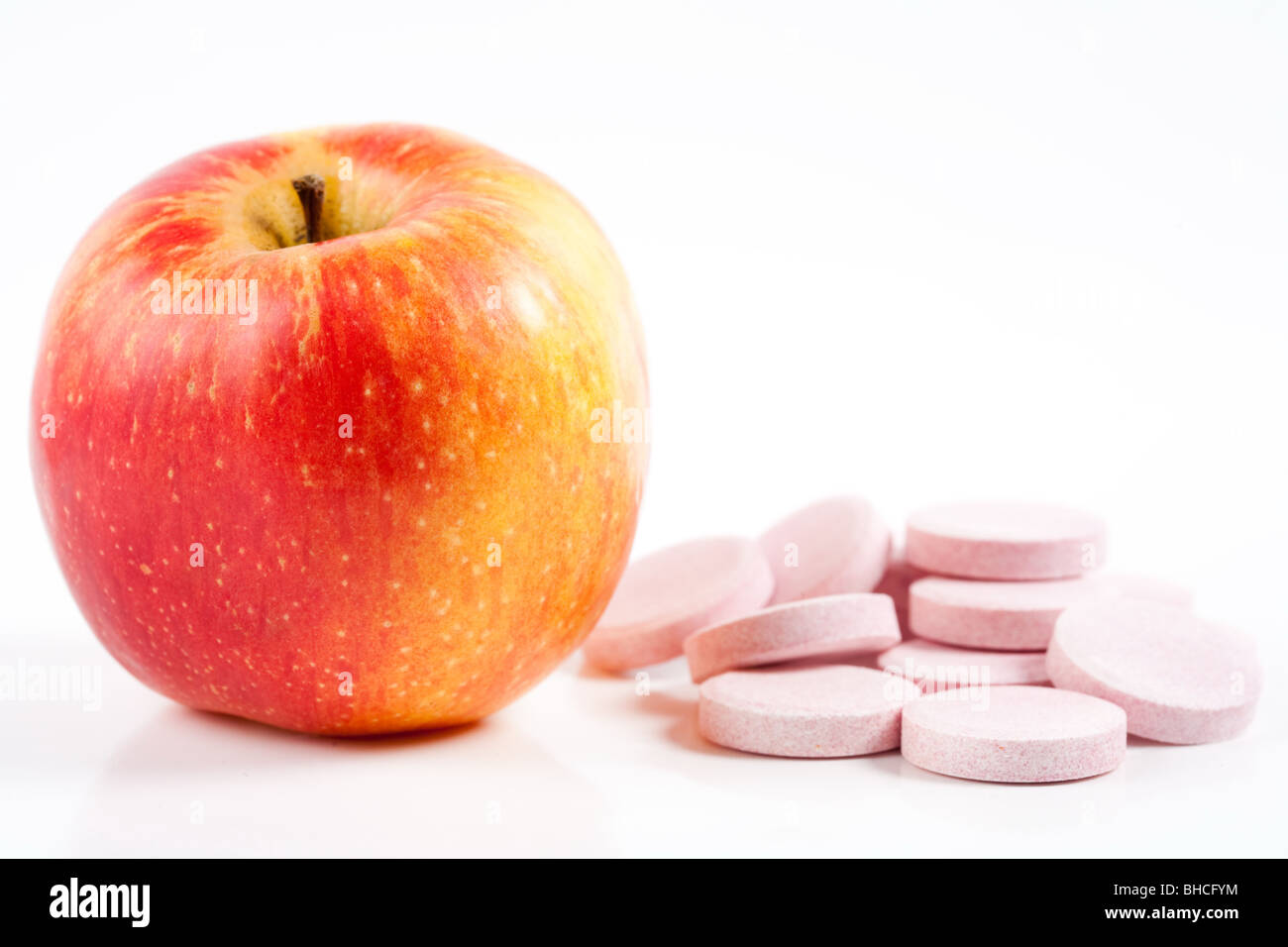 Mela Rossa vicino a pila di vitamina, concetto che illustra l'importanza del cibo naturale Foto Stock