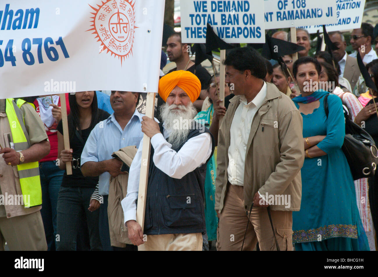 Ravidassia marzo contro la discriminazione di casta da sikh. Uomo che porta banner con simbolo, indossando turbante con barba completa Foto Stock