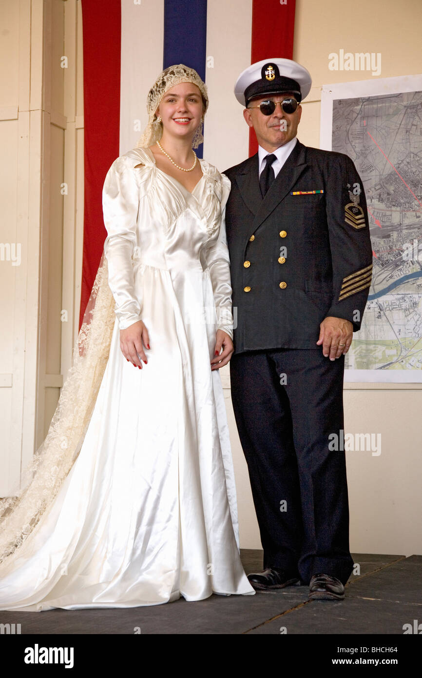 Sposa nel 1940 abito da sposa in posa con il suo padre vestito come un  ufficiale della Marina a stare di fronte alla bandiera durante una  rievocazione storica Foto stock - Alamy