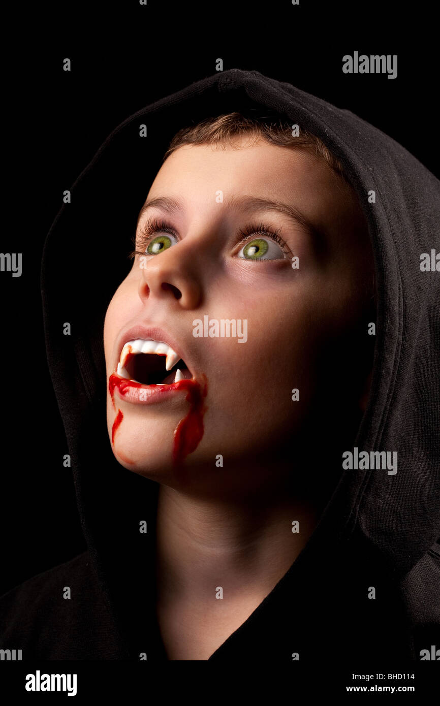 8 anni vecchio ragazzo vestito come un vampiro con sangue finto e zanne Foto Stock