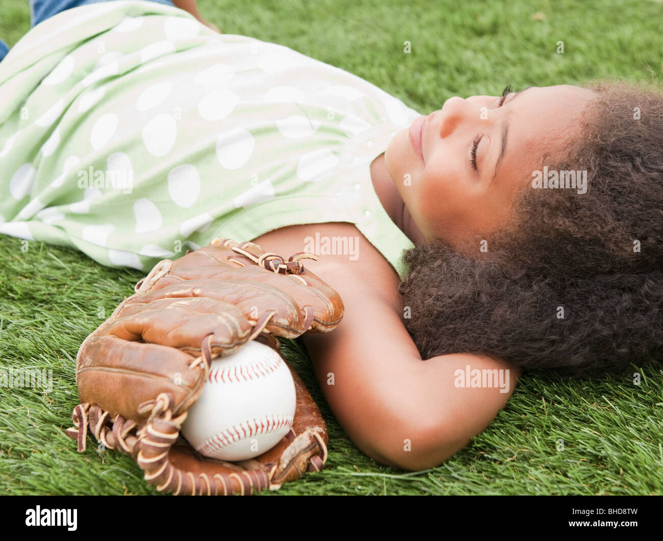 Razza mista ragazza posa accanto a Guanto baseball e sfera Foto Stock