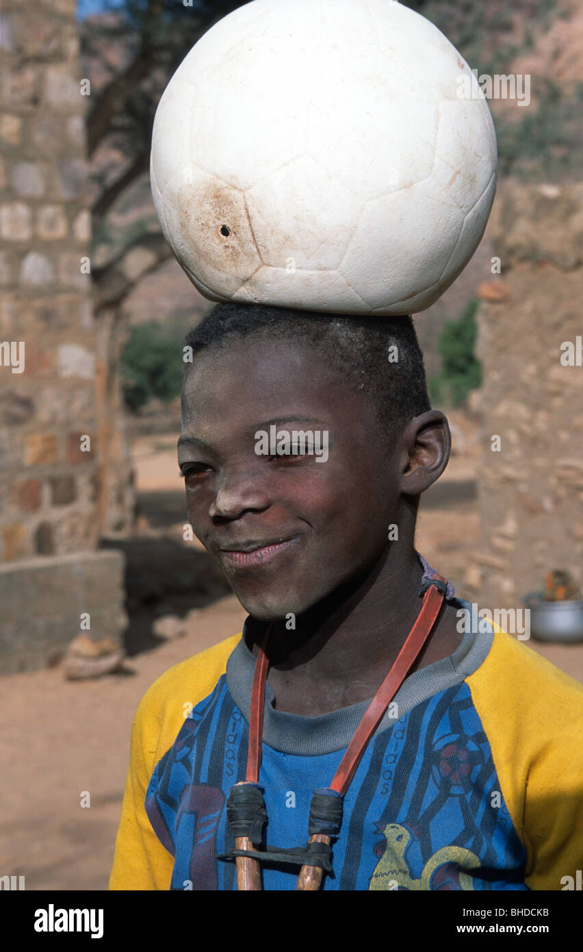 Un ragazzo con un calcio sgonfio sulla sua testa, Tereli, Pays Dogon del Mali. Foto Stock