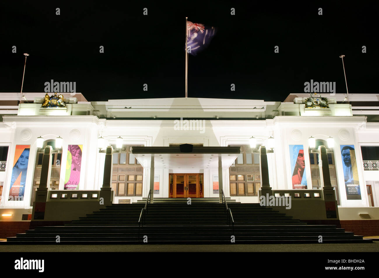 Museo della democrazia Australiana Old Parliament House Canberra // CANBERRA, territorio della capitale Australiana - il Museo della democrazia Australiana presso l'Old Parliament House è illuminato di notte. L'edificio storico, che un tempo fungeva da Parlamento australiano, mostra una bandiera australiana sul suo palo e grandi striscioni sulla sua facciata, promuovendo le sue mostre attuali. Questa vista notturna enfatizza la grandezza del monumento nazionale. Foto Stock