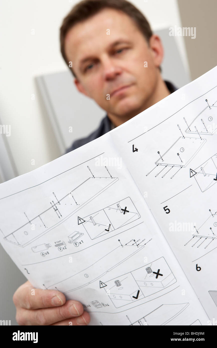 Uomo che legge le istruzioni di assemblaggio per il Flat Pack mobili Foto Stock