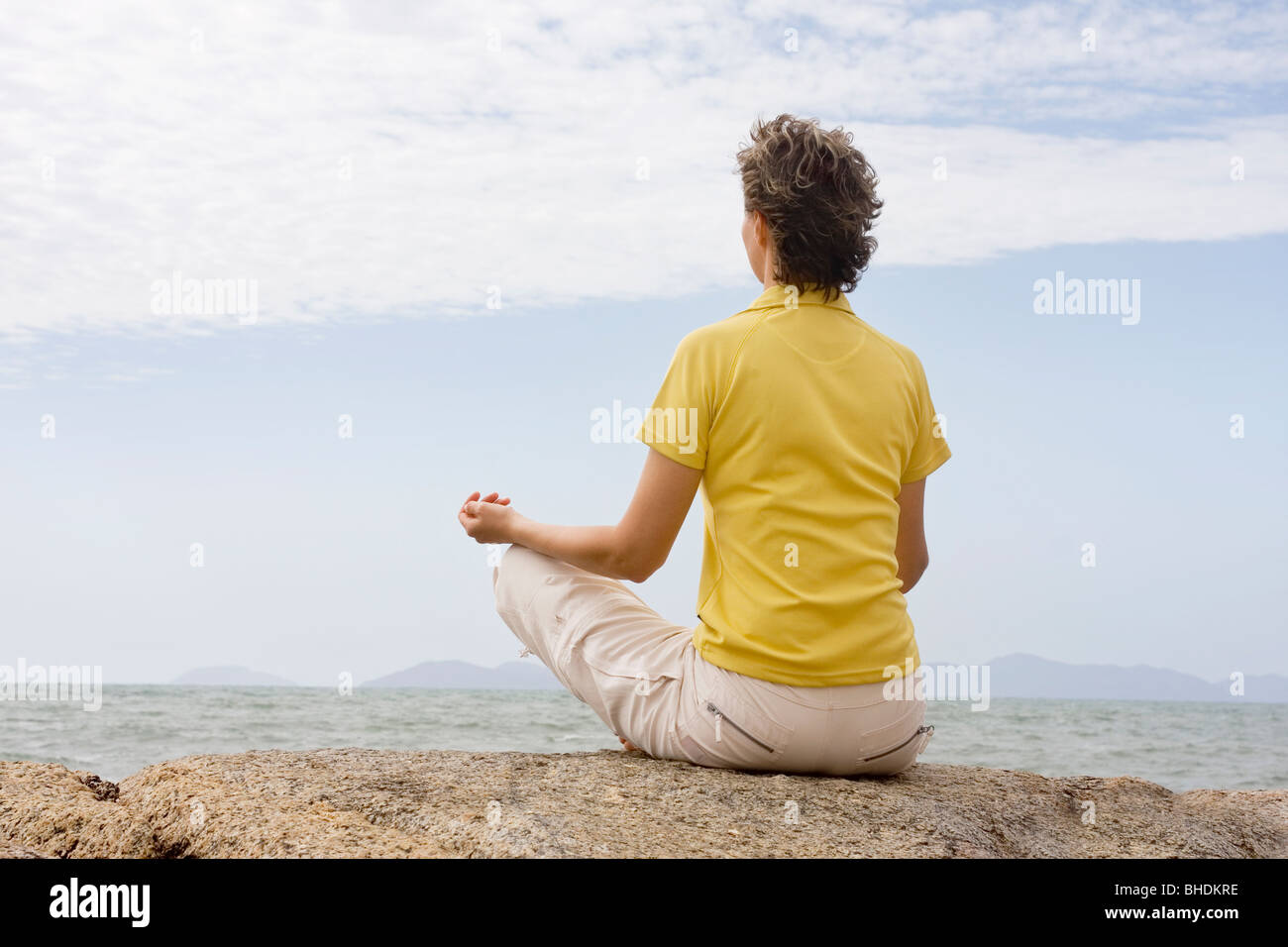Donna meditando su una roccia sul mare Foto Stock