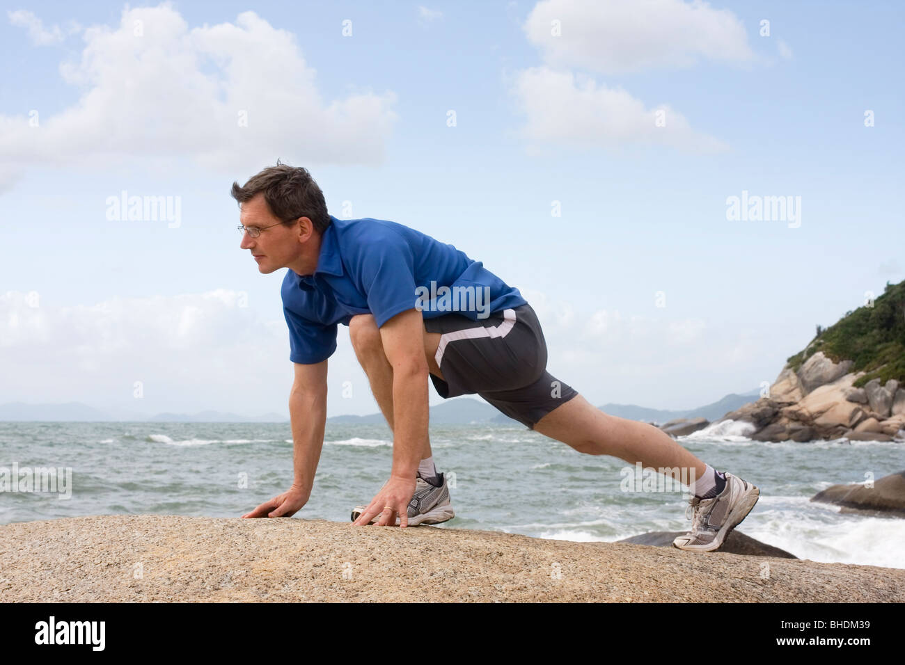 Pareggiatore fitness facendo esercizi su una roccia sul mare Foto Stock