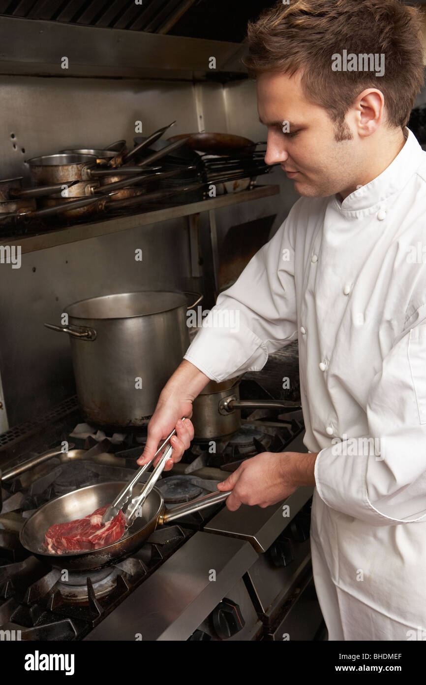 Lo Chef maschio preparazione di pasto sul fornello in Ristorante Cucina Foto Stock