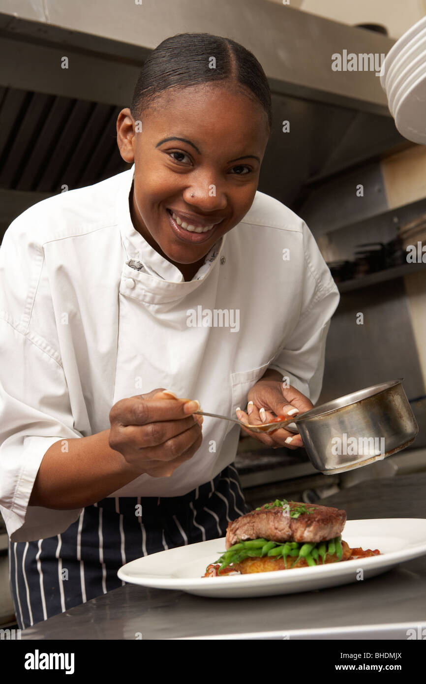 Chef salsa aggiungendo al piatto in un ristorante Cucina Foto Stock
