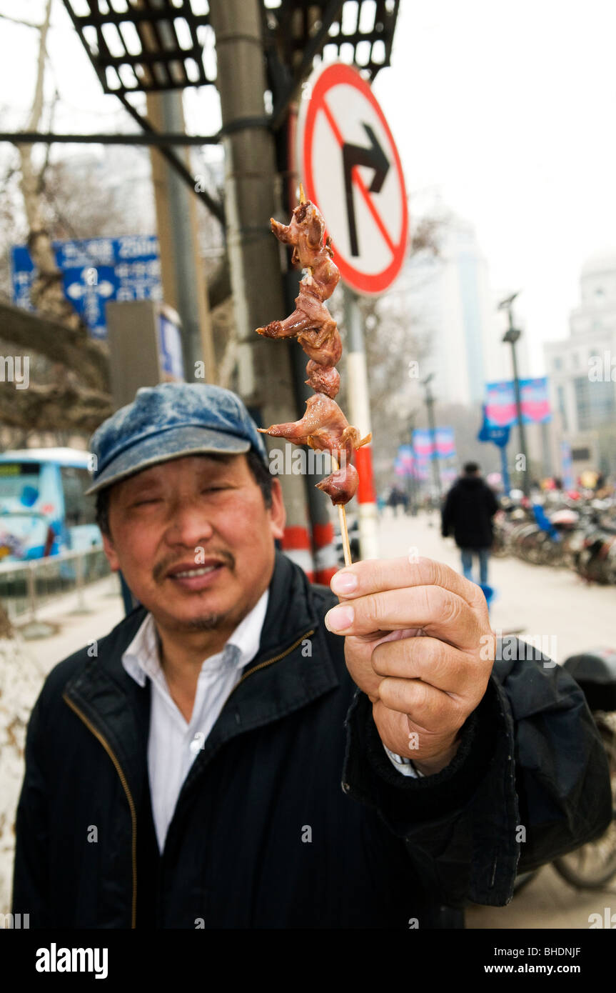 Un uomo con pulcini su uno spiedino. Foto Stock