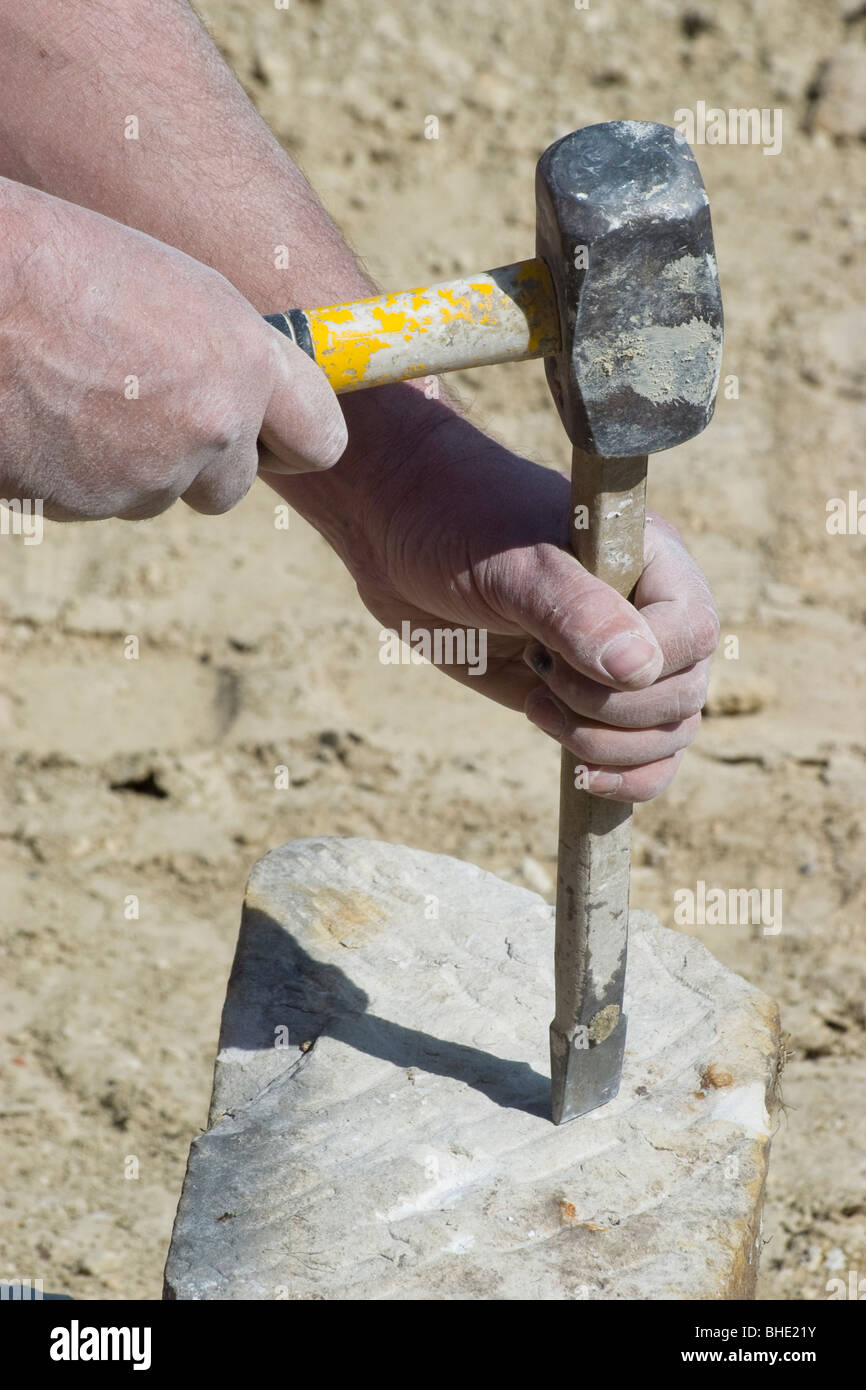 Una stone mason utilizza un martello e scalpello per rompere una grande  pietra Foto stock - Alamy