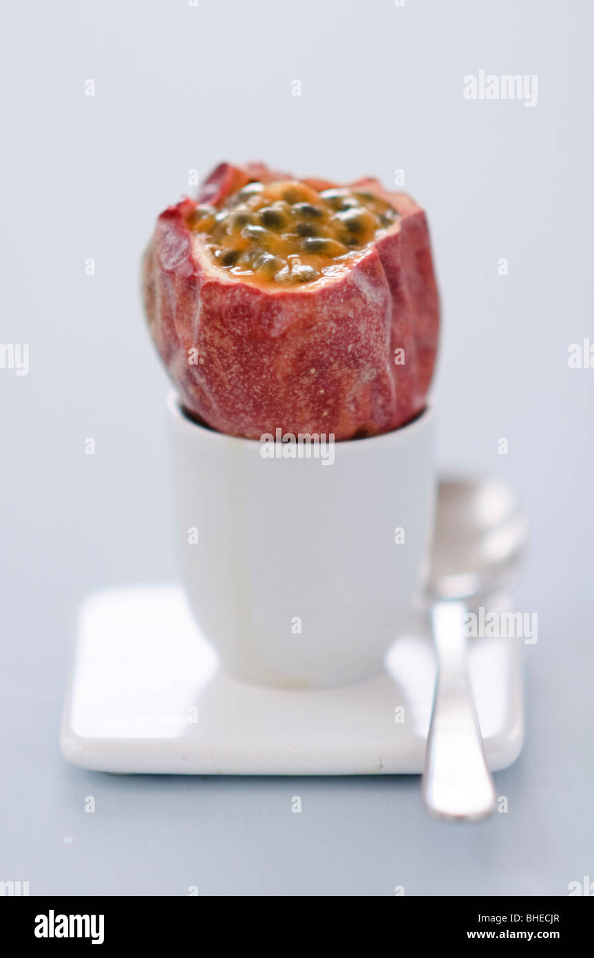 Frutti della passione con top cut off seduto in un uovo cup contro sfondo blu Foto Stock