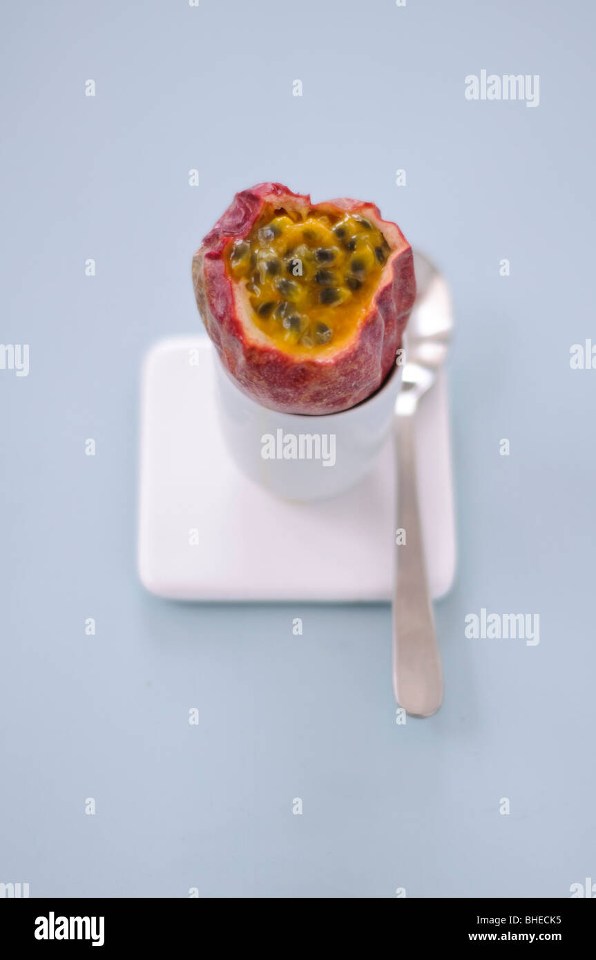 Frutti della passione con top cut off seduto in un uovo cup contro sfondo blu Foto Stock