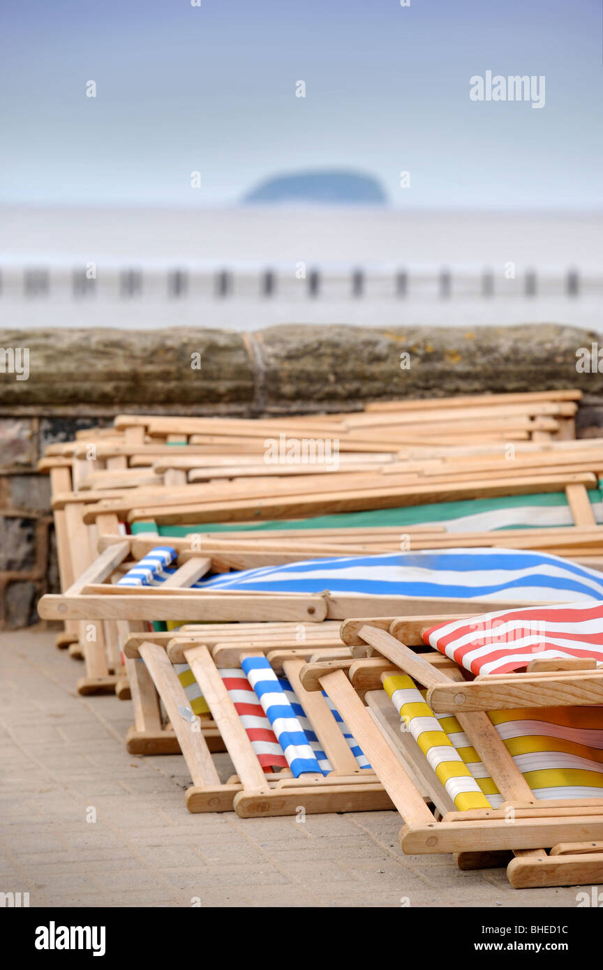 Sedie a sdraio da mura sul mare con ripide Holm island all'orizzonte a Weston-Super-Mare Somerset REGNO UNITO Foto Stock