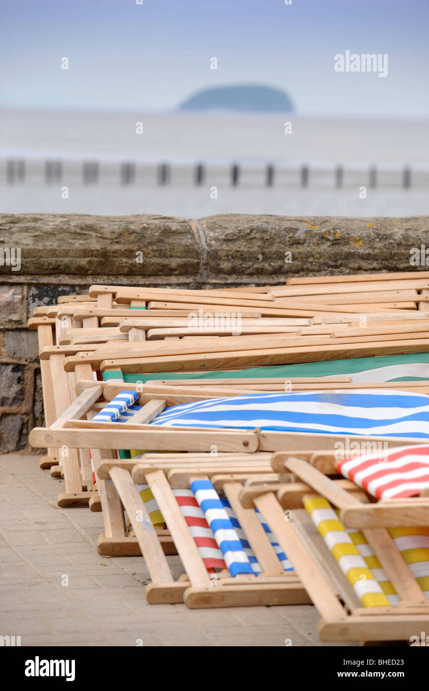 Sedie a sdraio da mura sul mare con ripide Holm island all'orizzonte a Weston-Super-Mare Somerset REGNO UNITO Foto Stock