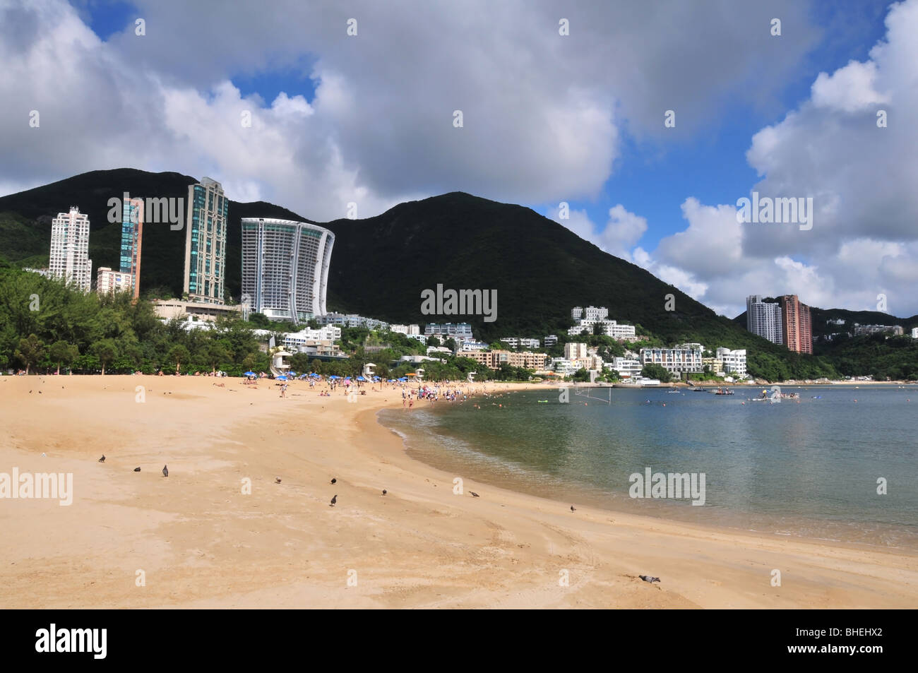 Vista della spiaggia affollata, curvando verso est verso una collina silhouette dietro gli appartamenti di lusso, Repulse Bay, Hong Kong Foto Stock