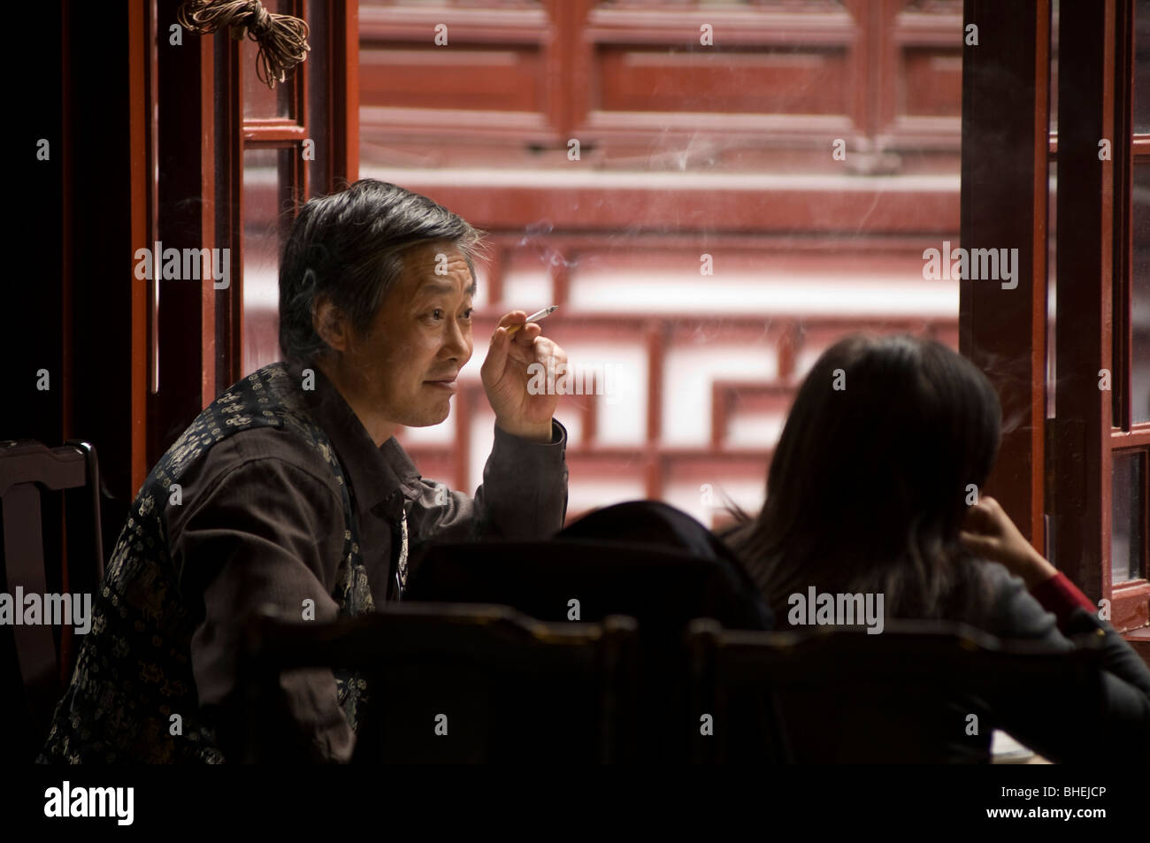 Uomo di fumare in un ristorante nel giardino di Yu Bazaar, Shanghai, Cina e Asia Foto Stock