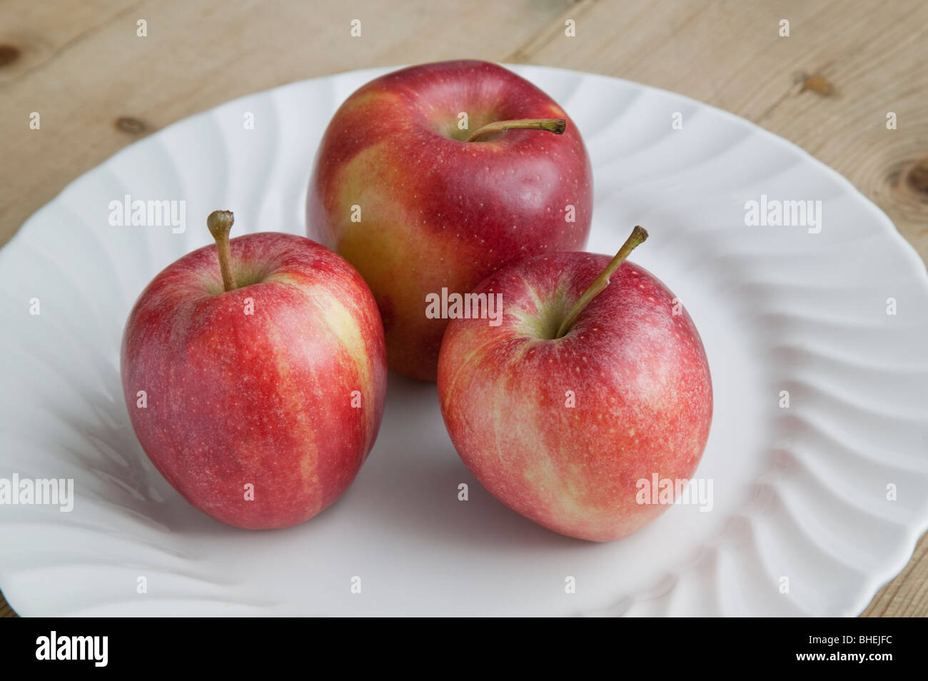Rosso di mangiare le mele sulla piastra bianca sul tavolo di legno Foto Stock