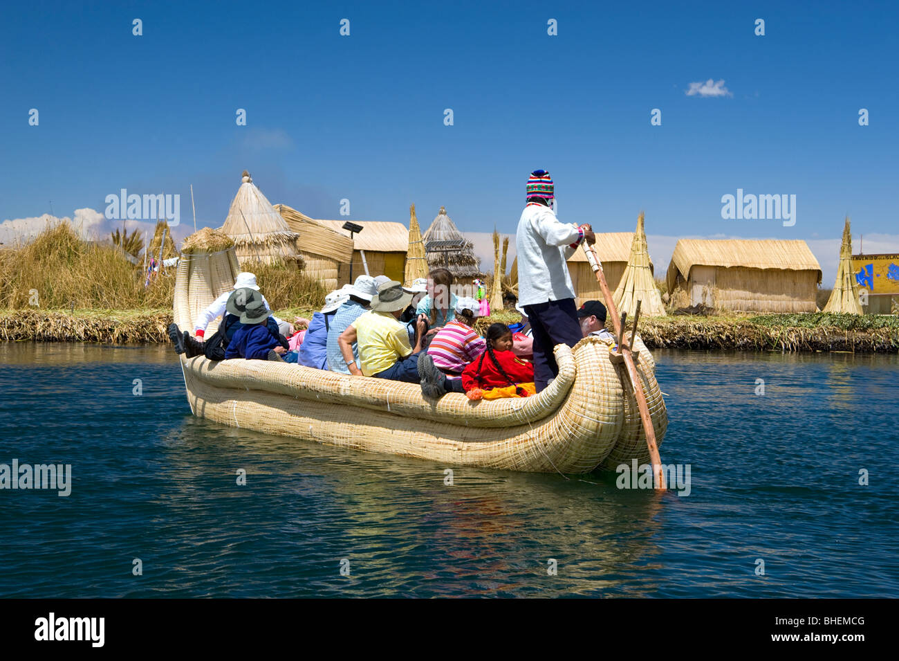 Un uomo locale da Uros Islandof Samary pagaie un tradizionale totora reed barca piena di turisti Foto Stock