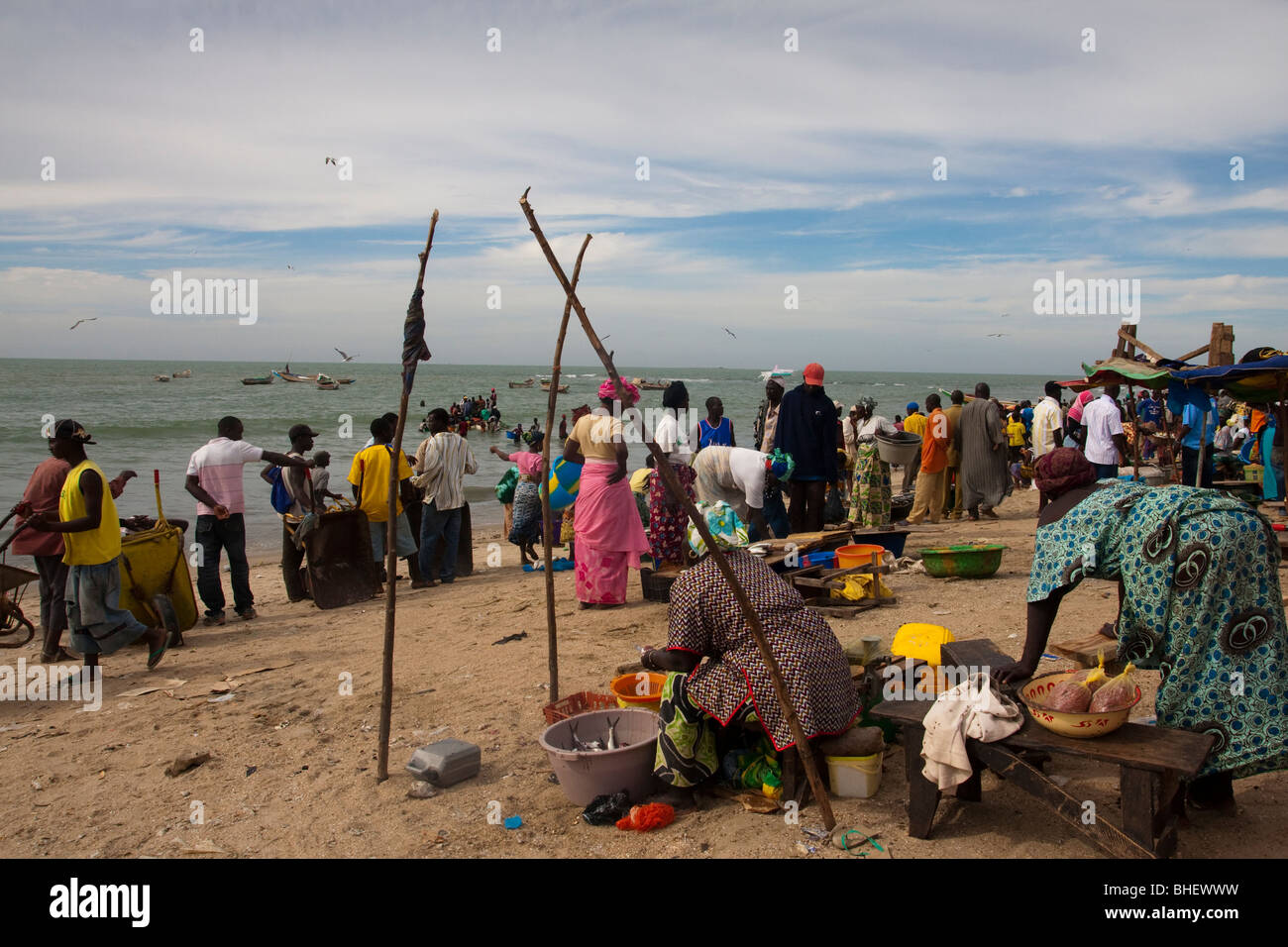 La popolazione locale e verniciato colorato di barche da pesca in Tanji villaggio di pescatori Gambia Africa Foto Stock