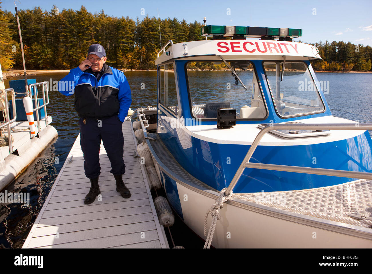 La guardia di sicurezza a parlare su un telefono cellulare a un dock Foto Stock