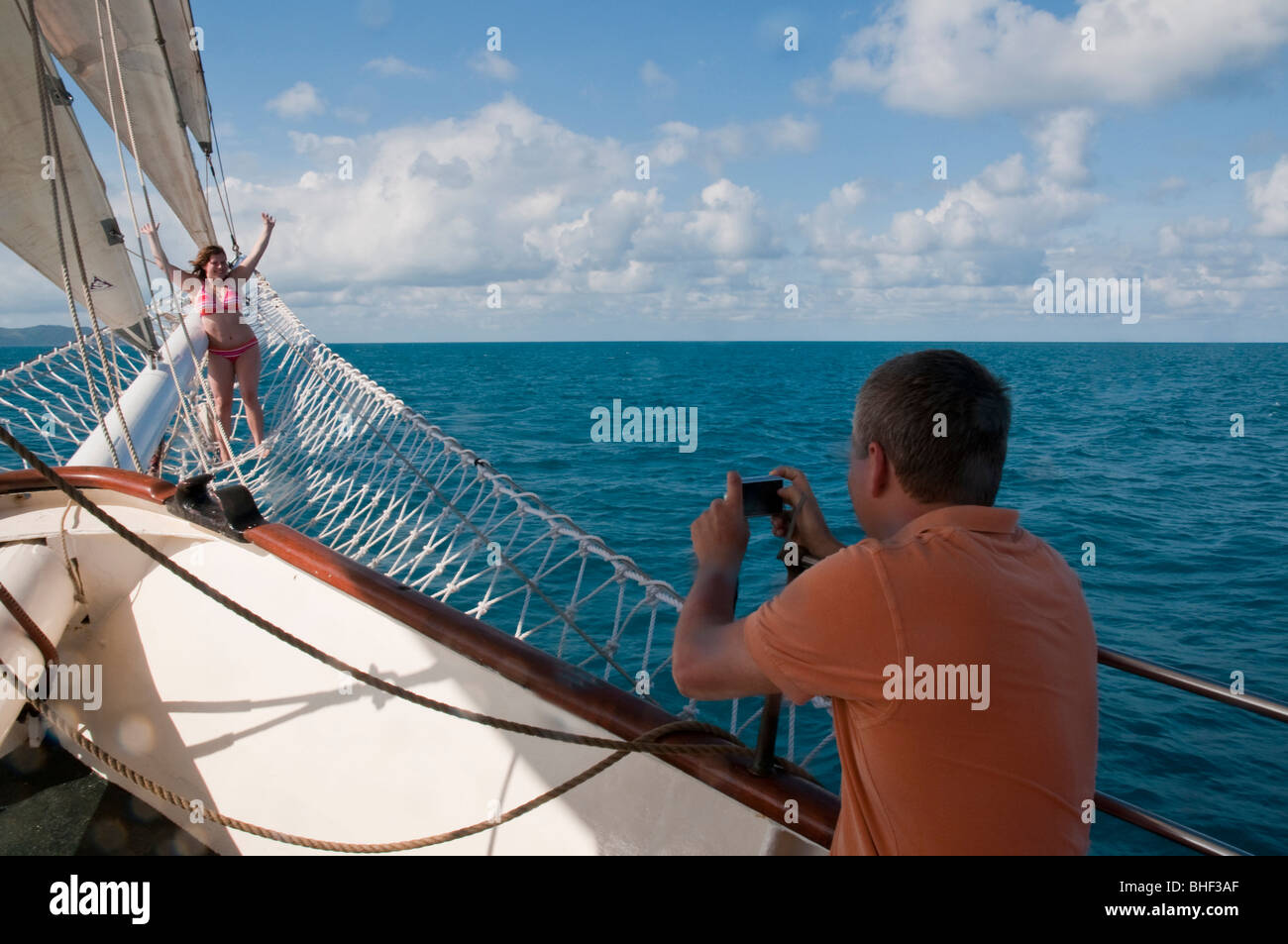 L'uomo fotografare la giovane donna in prua al netto di un tall ship Foto Stock