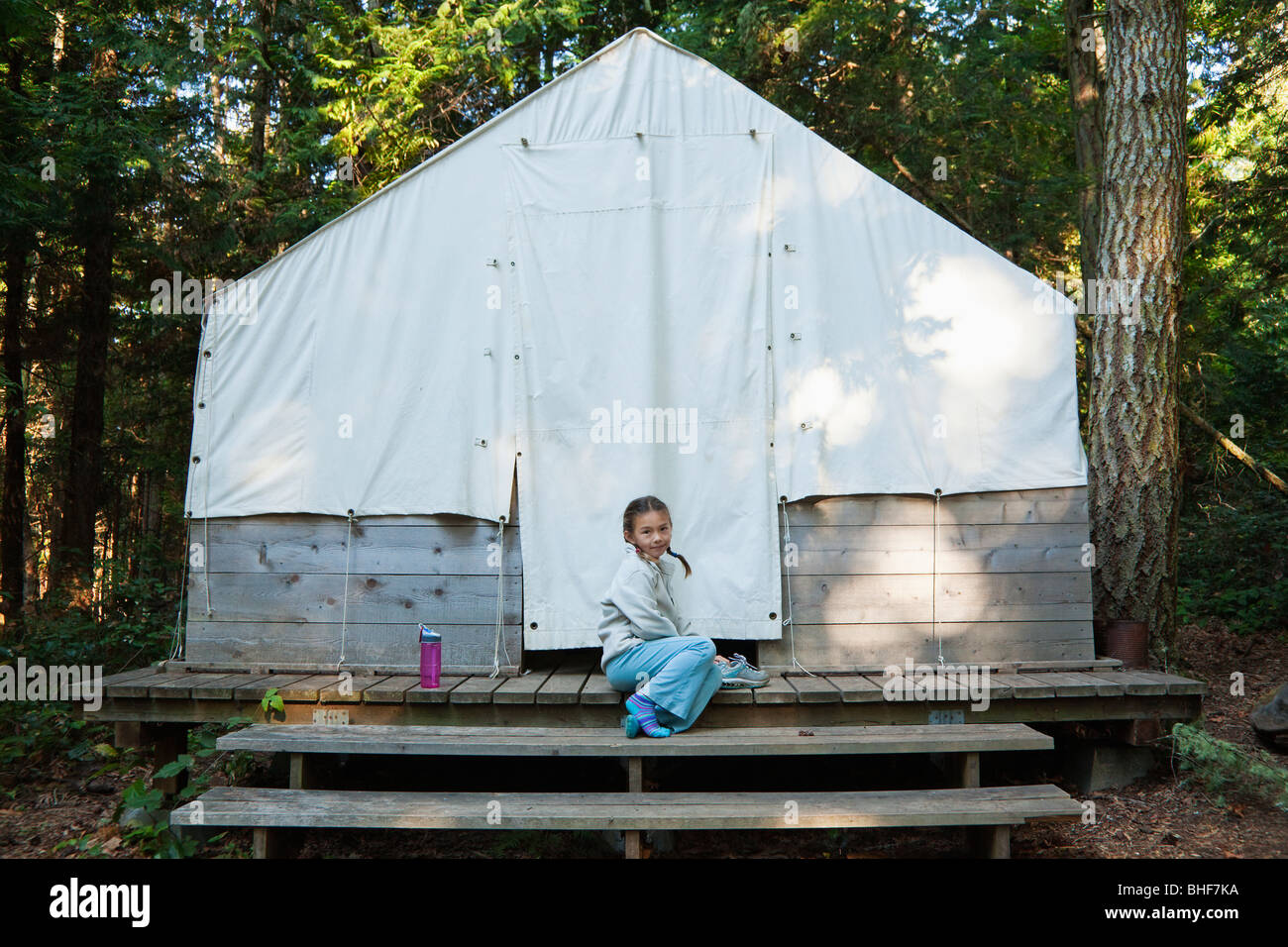 Razza mista ragazza seduta vicino alla tenda Foto Stock