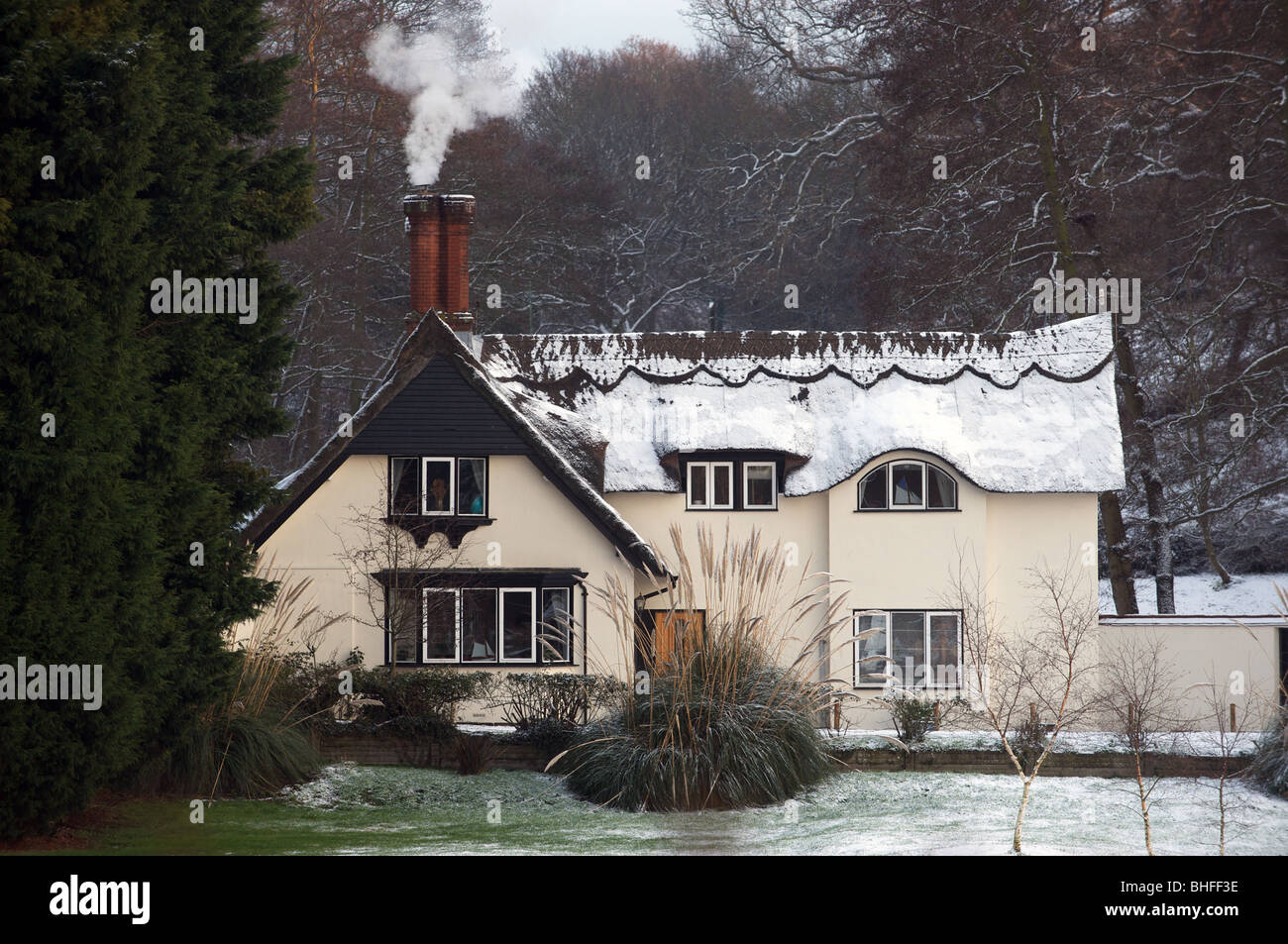 Cottage con tetto in paglia in parte coperte di neve Foto Stock