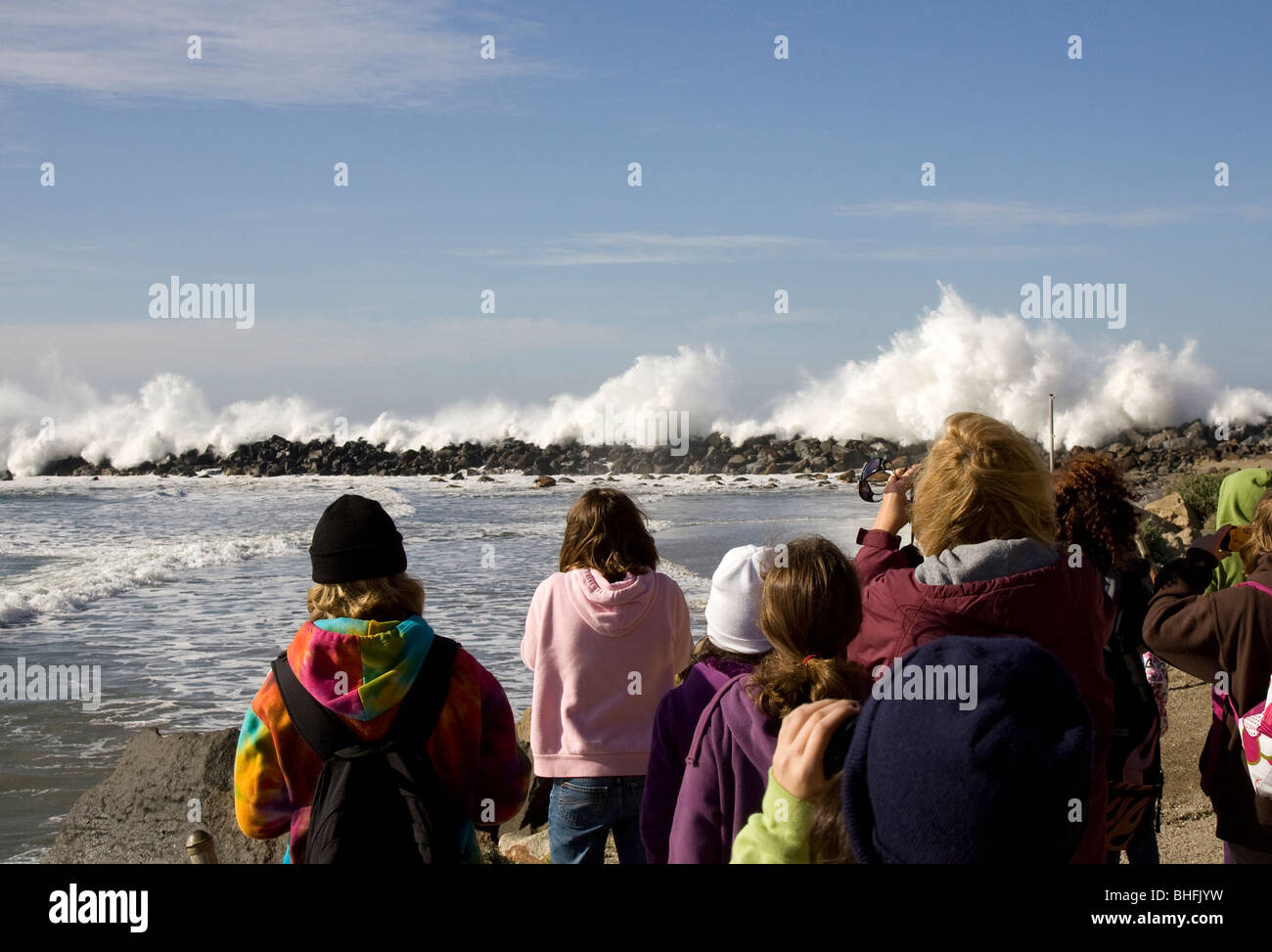 Gruppo di persone che guardano onde infrangersi sulla scogliera Foto Stock