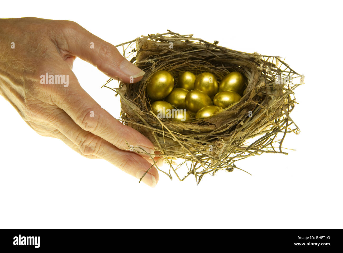 Senior donna raggiungendo per bird's Nest con piccole uova d'oro, studio shot Foto Stock