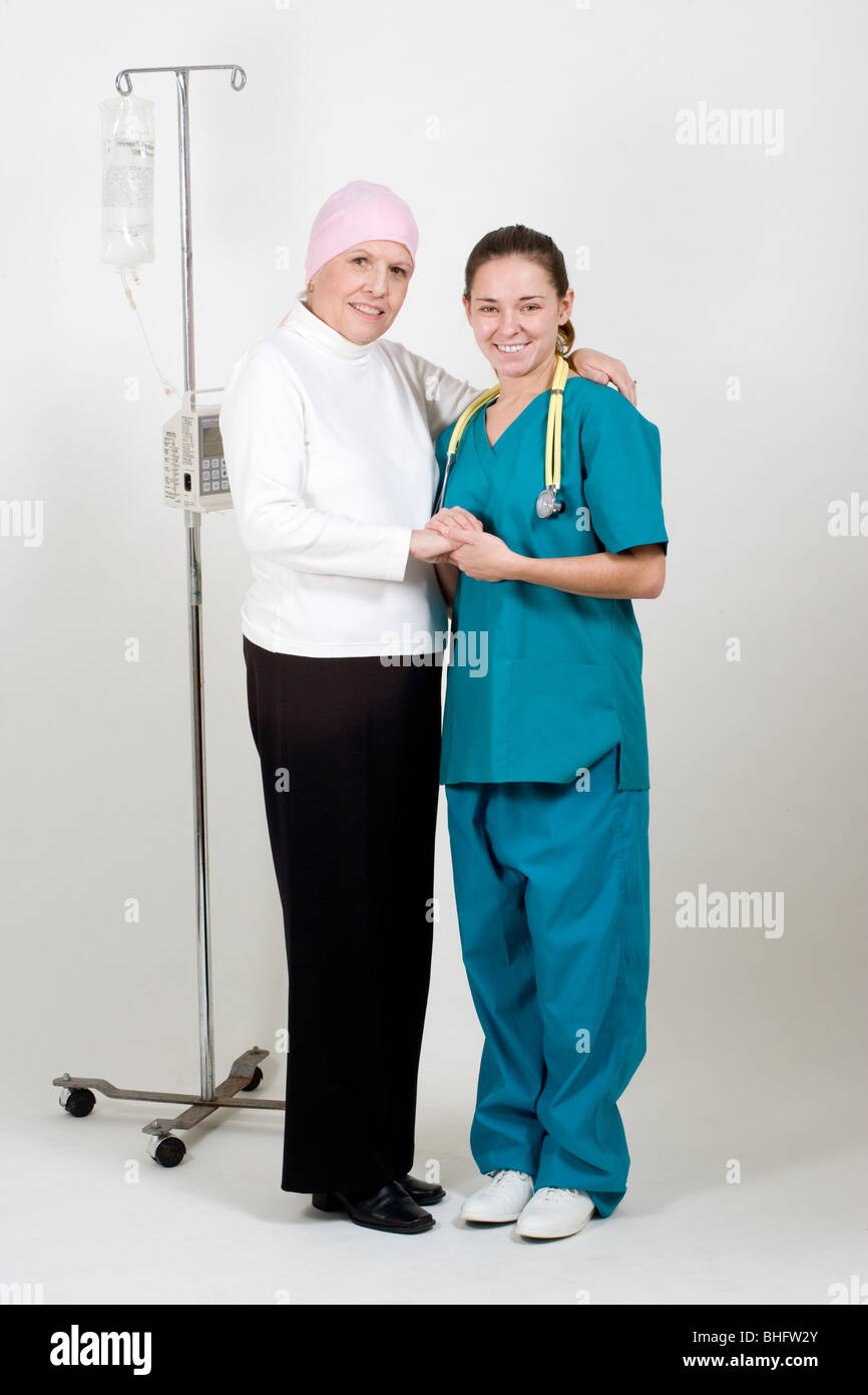 L'infermiera consolante senior donna su flebo IV sorridente e tenendo la sua mano. Foto Stock