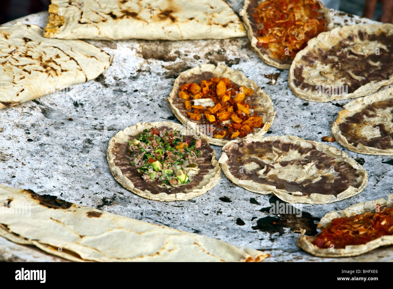 Taco gusci con una varietà di deliziosi condimenti cotta su un fuoco di carbone sono pronti a servire a un marciapiede stallo in Oaxaca Foto Stock