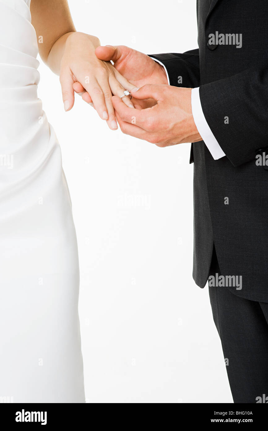 Lo sposo il posizionamento di un anello sul dito spose Foto Stock