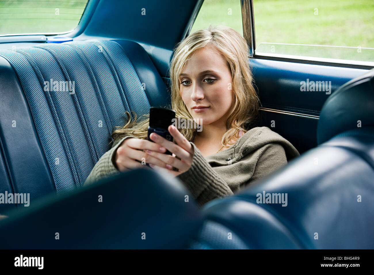 Giovane donna in auto con il cellulare Foto Stock