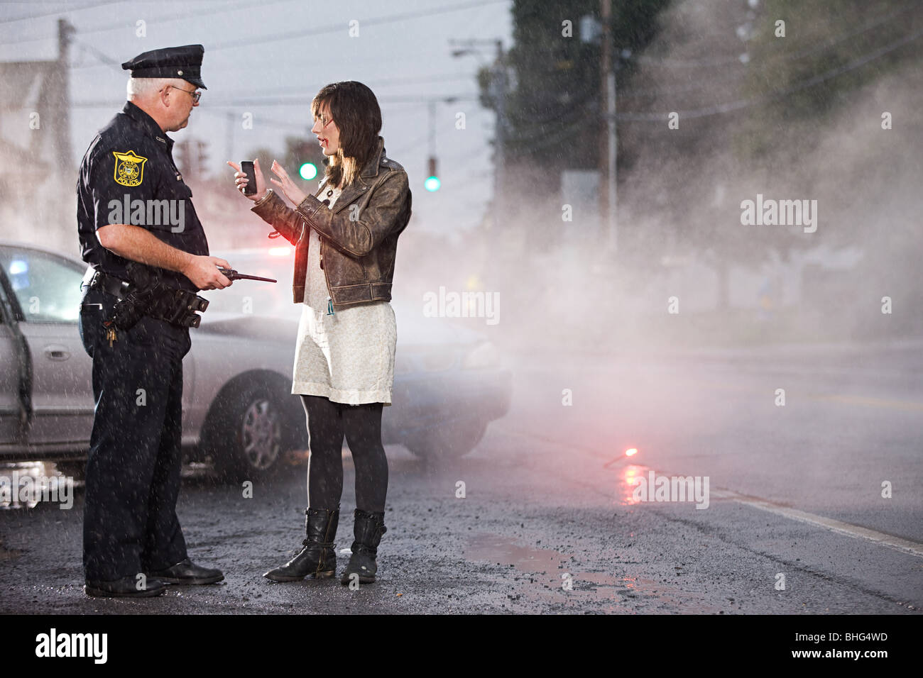 Giovane donna e funzionario di polizia a scena di crash Foto Stock