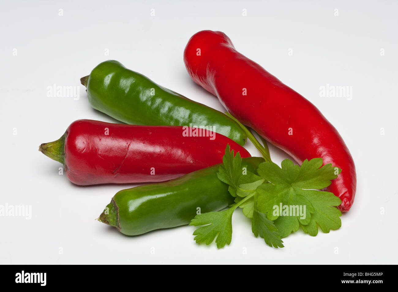 Rosso e peperoncini verdi con prezzemolo e basilico su uno sfondo semplice Foto Stock
