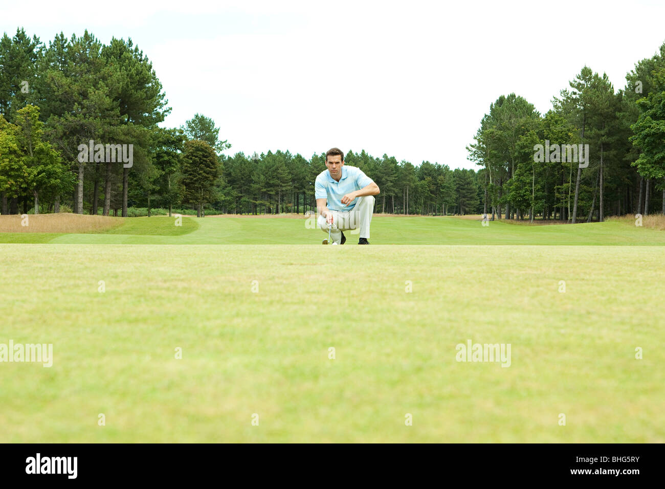 Golfista maschio accovacciato sul fairway Foto Stock