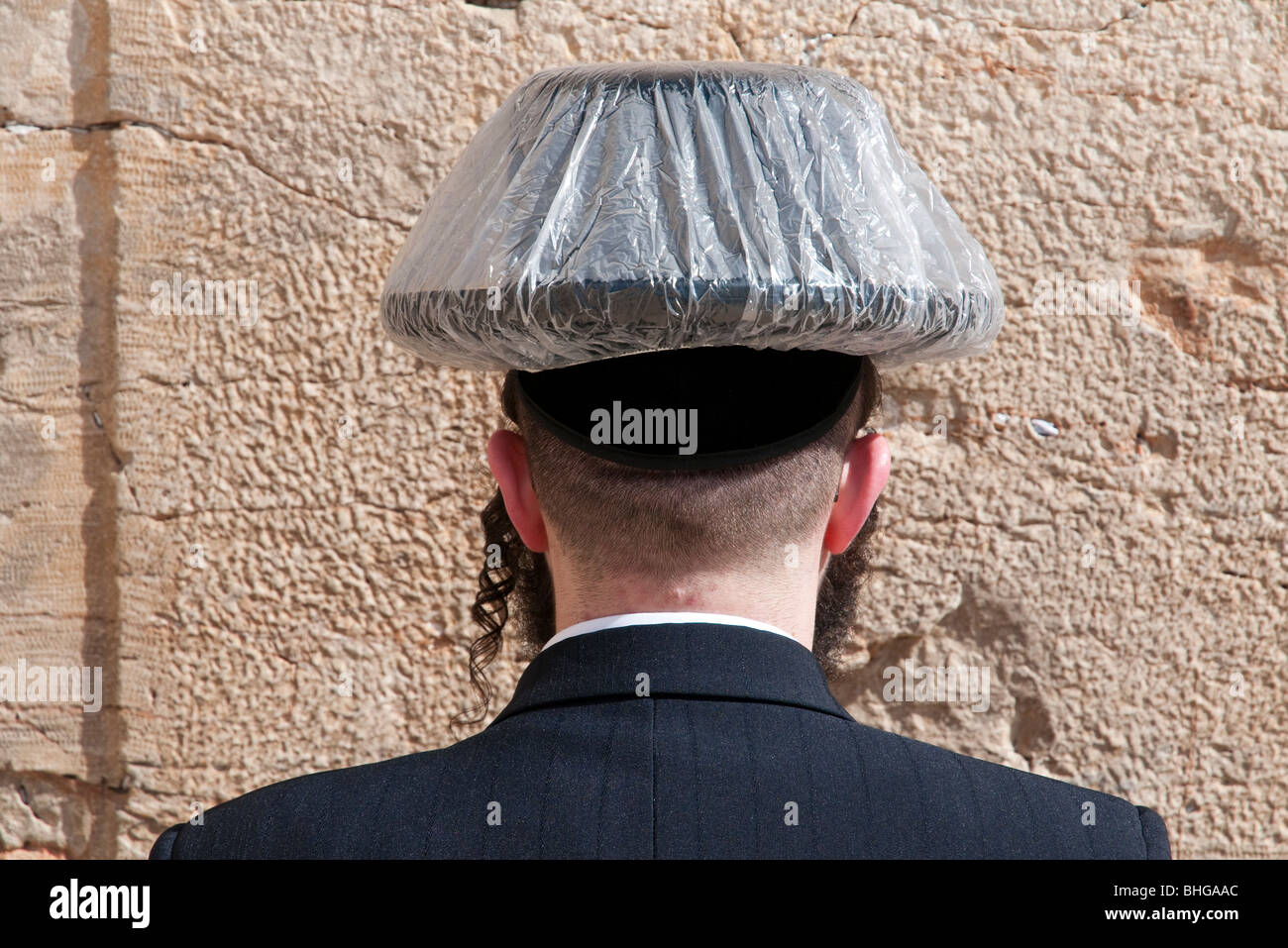 Ebreo ortodosso con hat avvolto in un sacchetto di plastica in preghiera al Muro Occidentale Foto Stock